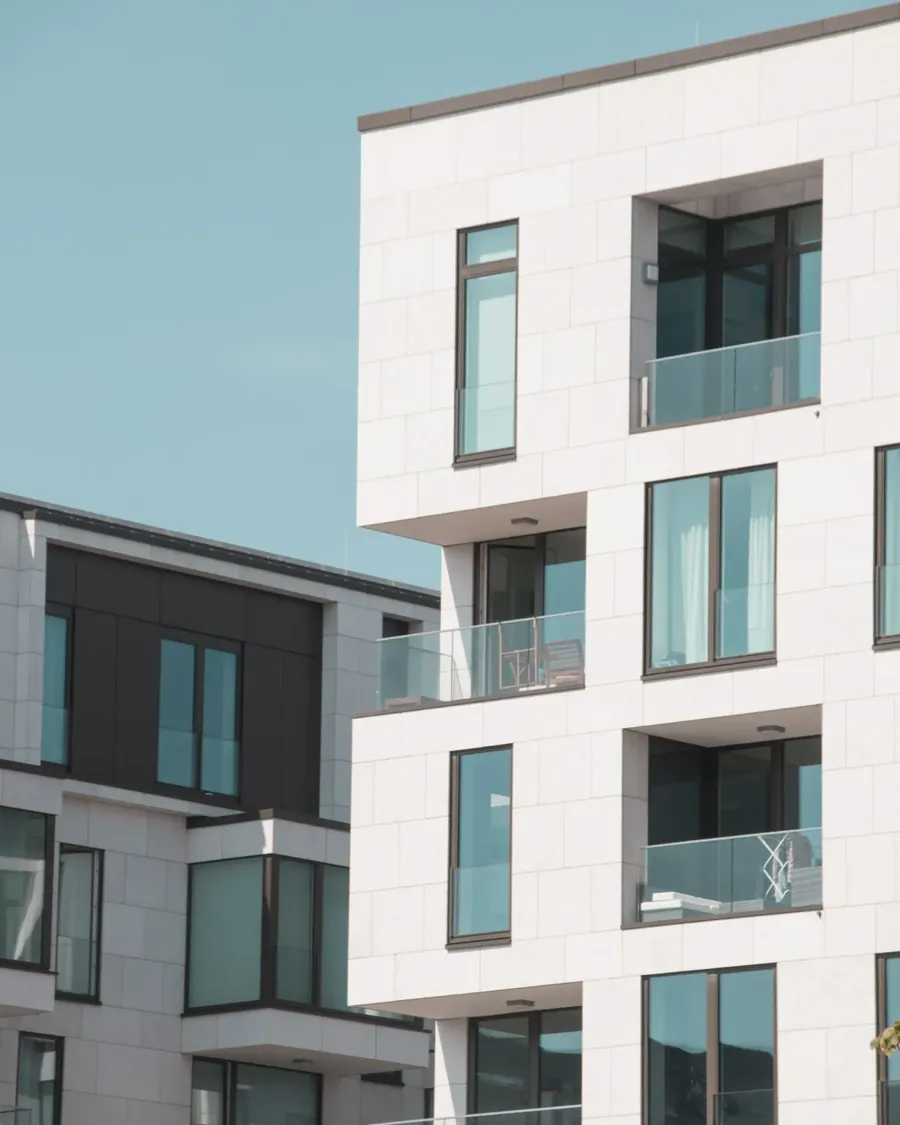 Modern apartment facade with glass balconies and white cladding